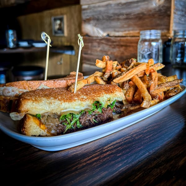 Two gourmet sandwiches with pulled pork and arugula, served with a side of crispy french fries.