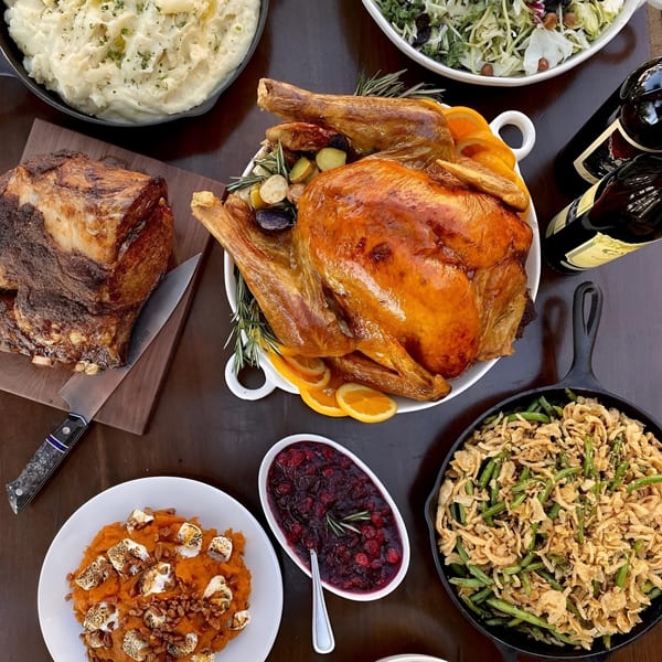 A holiday feast with roasted turkey, prime rib, mashed potatoes, green bean casserole, and cranberry sauce.