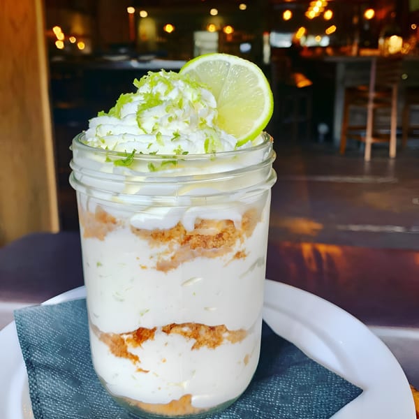 Key lime pie parfait in a mason jar with whipped cream, lime zest, and a lime slice.